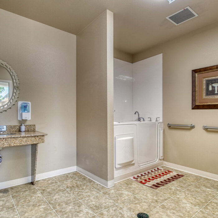 Accessible senior bathroom with walk-in tub and support bars at Grace Assisted Living