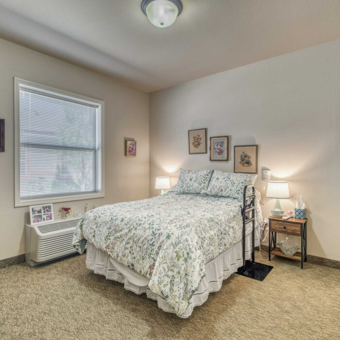 Bright and cheerful senior bedroom with floral bedding and family photos.