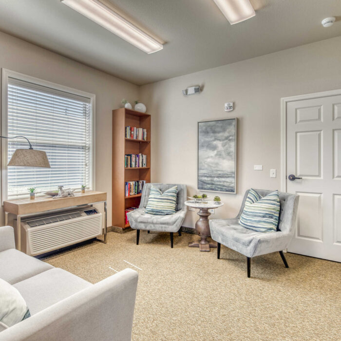 Cozy assisted living reading room with plush chairs and bookshelves in Boise-Eagle, Idaho.