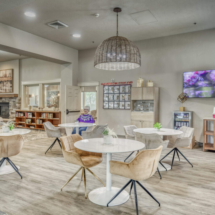 Elegant social cafÃ© area for seniors with modern decor, fireplace, and indoor seating.
