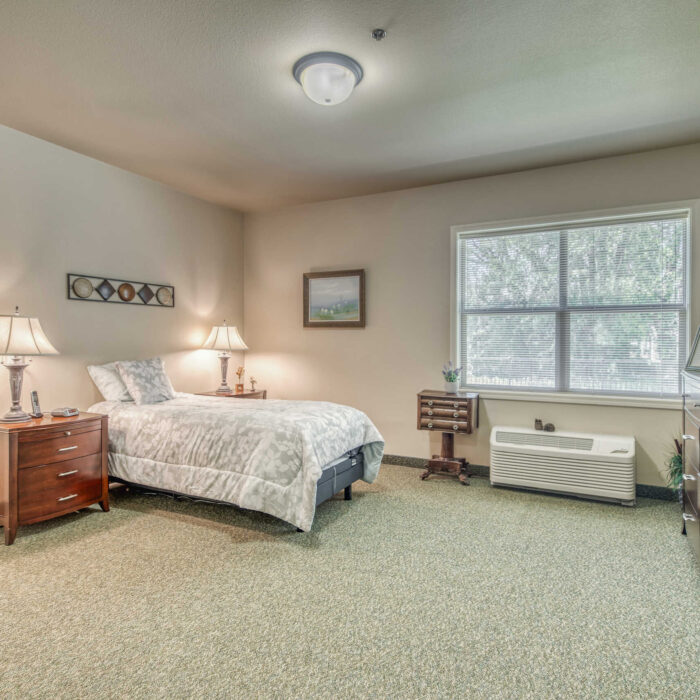 Private resident bedroom with large window and traditional furnishings