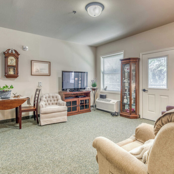 Resident living room with TV and wood furnishings at Grace Assisted Living