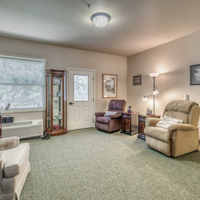 Spacious living room with recliners and natural light in assisted living suite