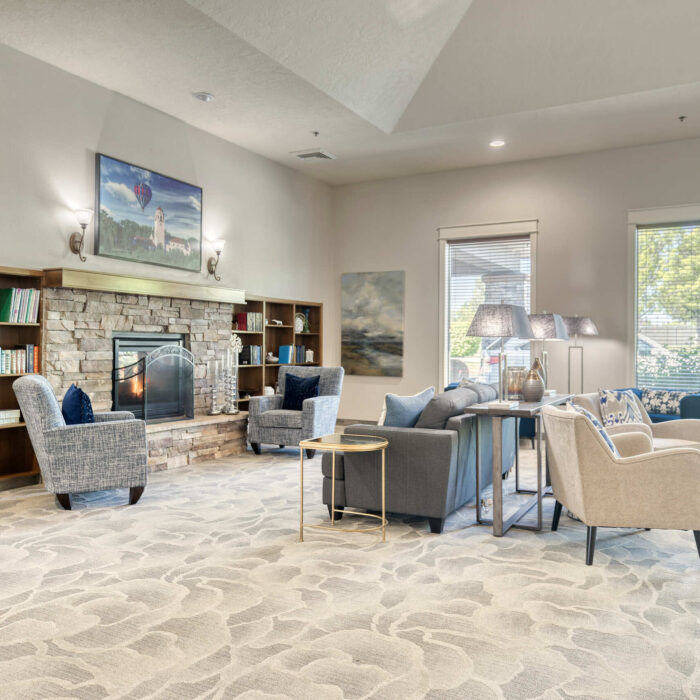Bright senior lounge with bookshelves, fireplace, and relaxing seating options