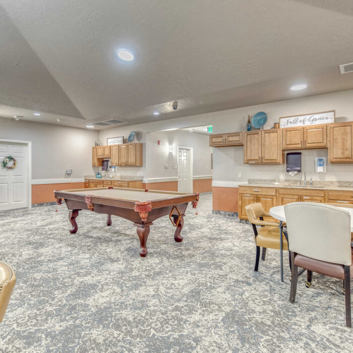 Activity and billiards area at Grace Assisted Living Meridian with warm lighting and kitchen access.
