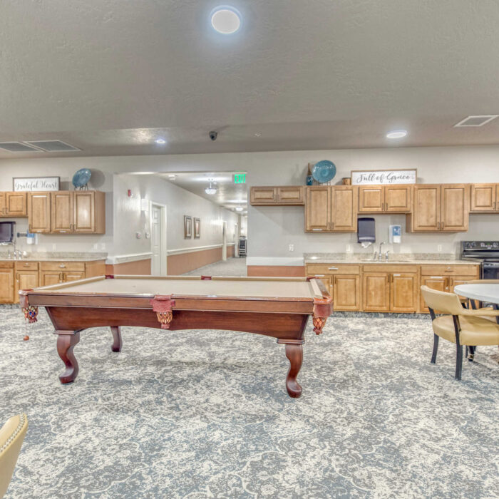 Community lounge and kitchen space with billiards table at Grace Assisted Living Meridian.