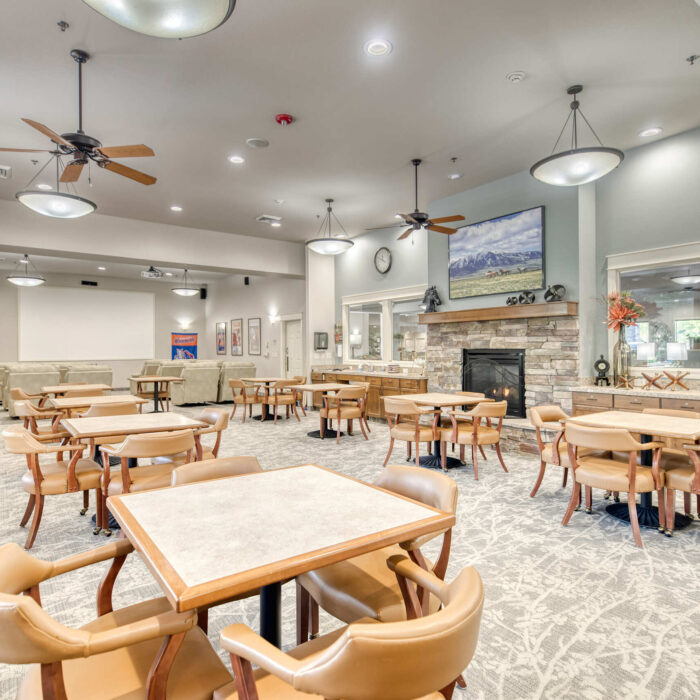 Open community room with dining tables and a fireplace at Grace Assisted Living