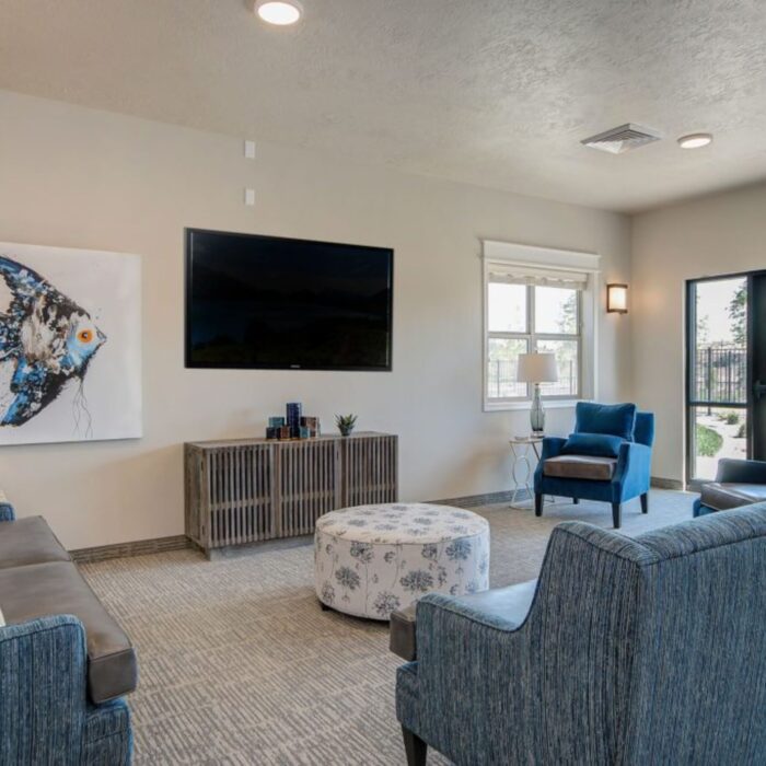 Modern senior lounge with TV and blue seating at Grace Memory Care Caldwell